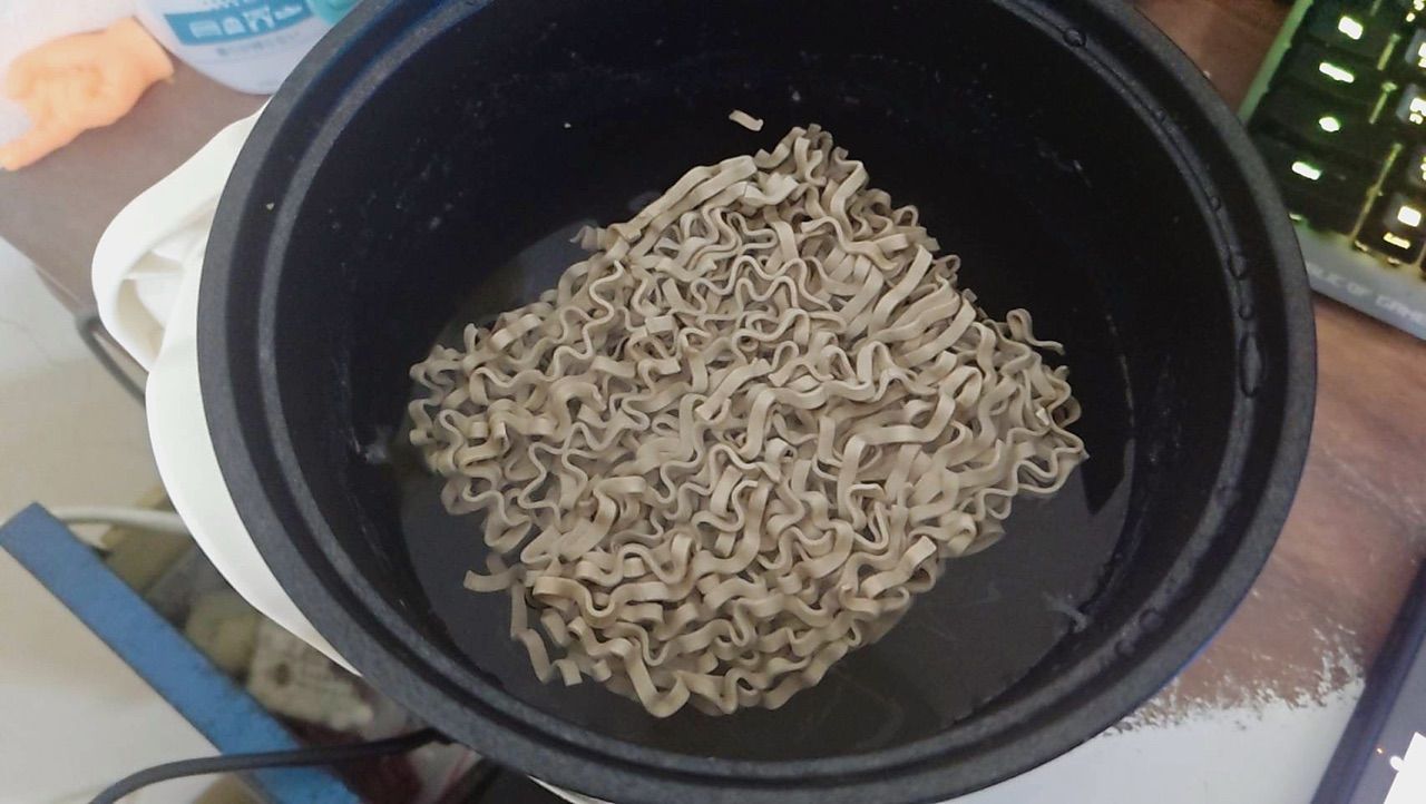 鍋中烹煮小蘭州蕎麥麵的實拍照片，可見麵體與湯水狀態